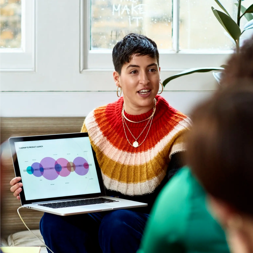 A professional presents a graphic on their laptop screen to their colleagues.