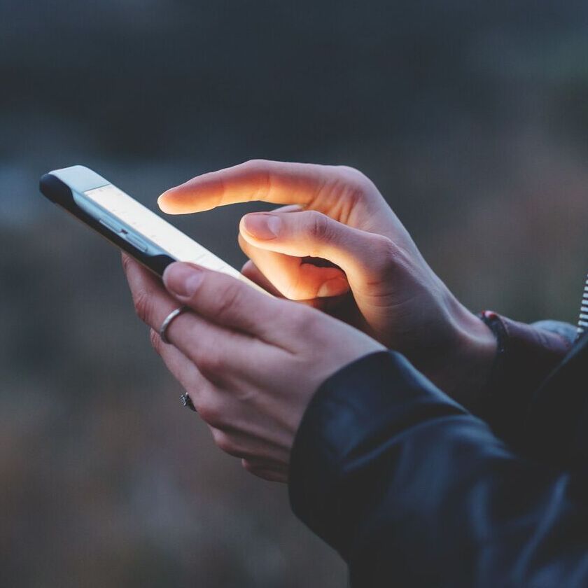 A hand holding a phone and swiping with their pointer finger