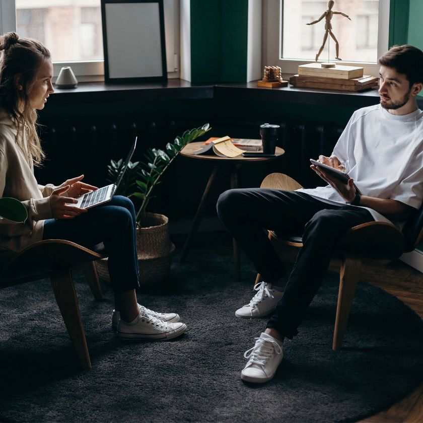 Two people discuss workflow management, using a laptop and tablet to organize tasks and collaborate efficiently.