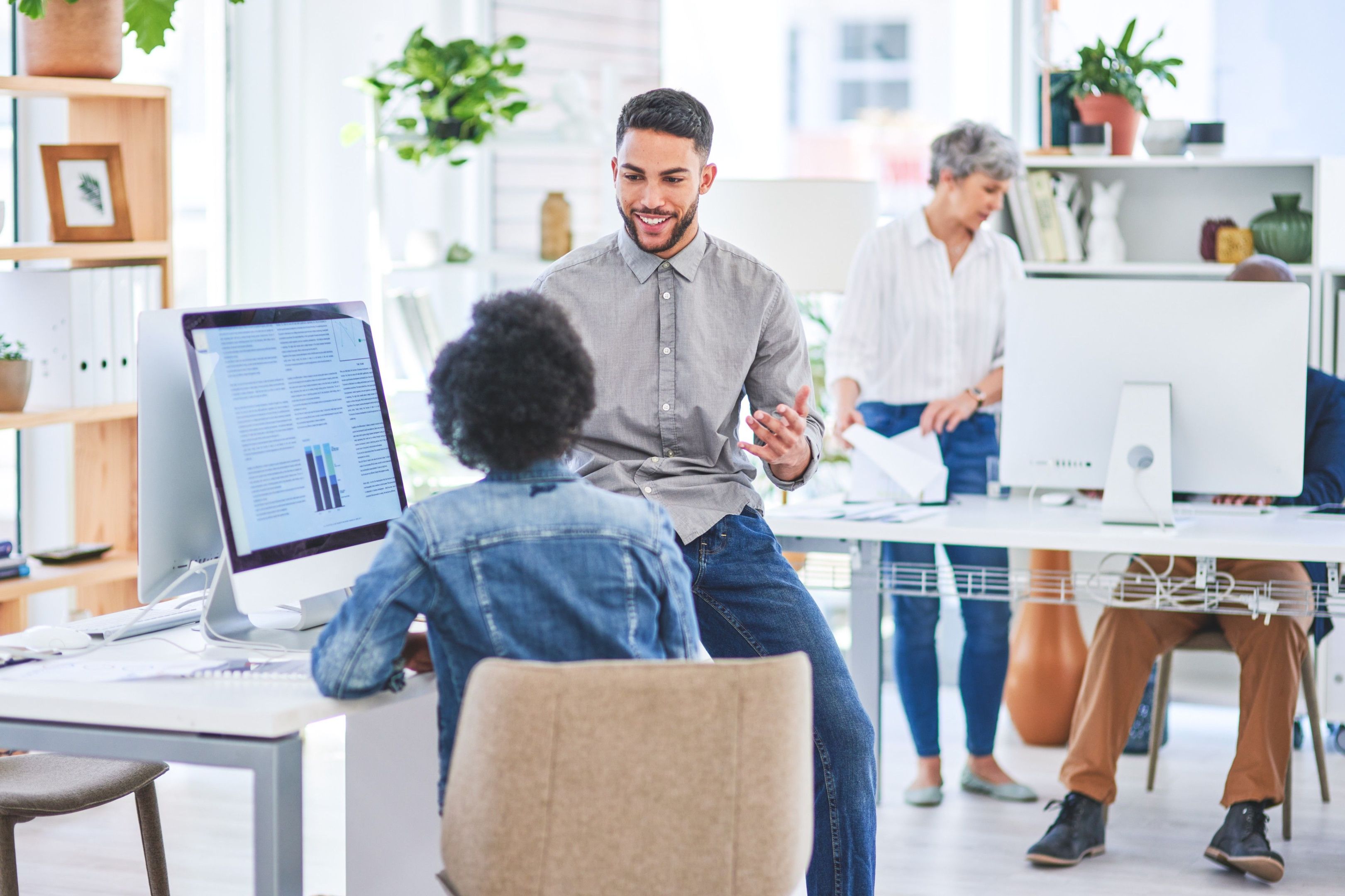 People at computer desks interact in an office setting