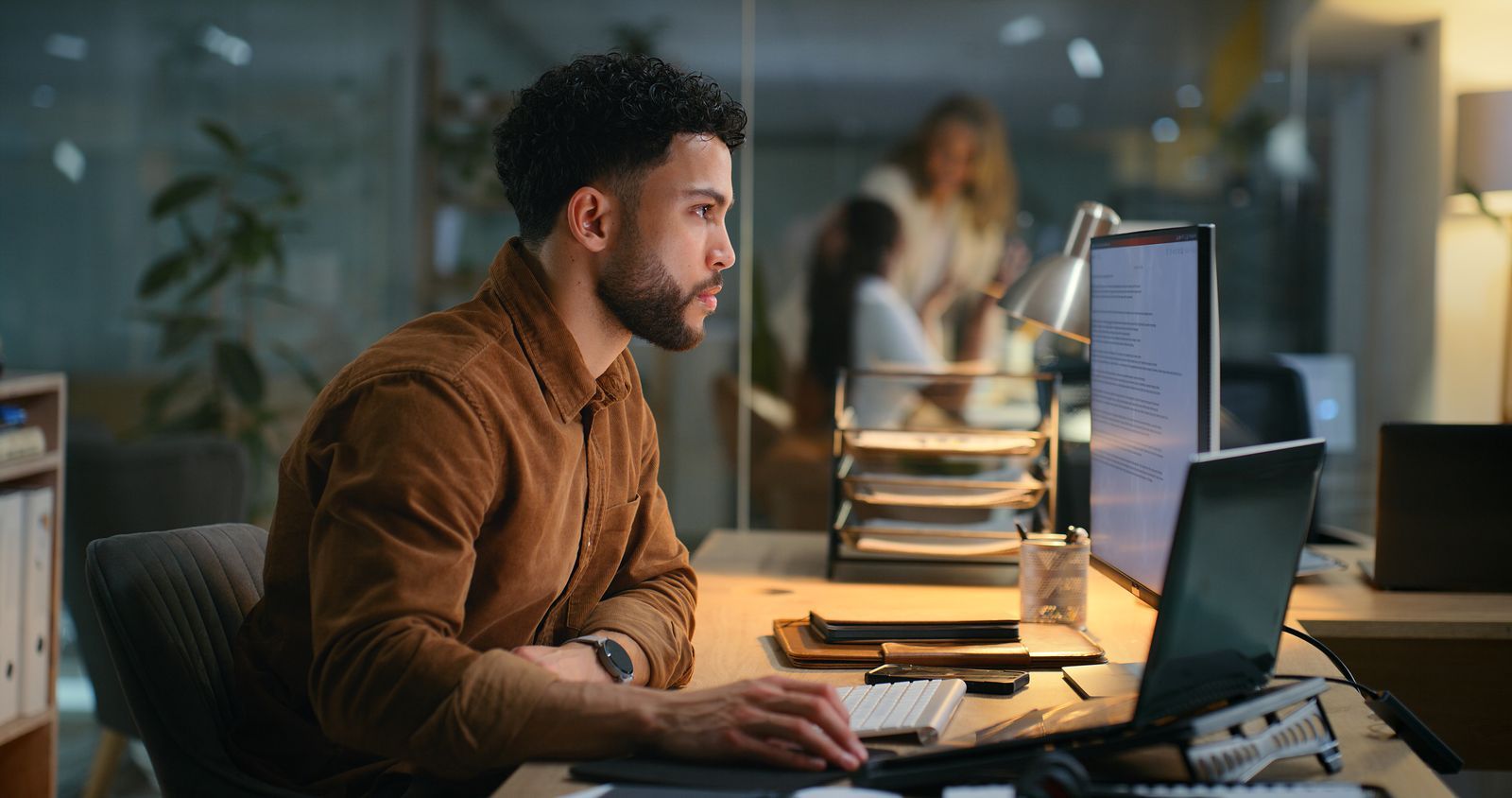 Man working at a desktop computer in an office at night